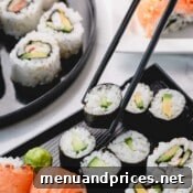 Crafting Delicious Sushi at Home 10 Cucumber rolls with one piece picked up with chopsticks.