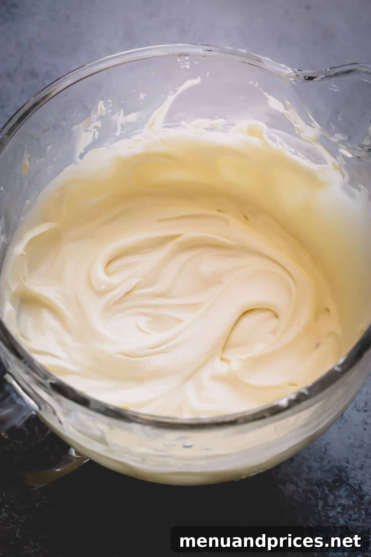 Effortless Cream Cheese Frosting Perfection 6 A glistening glass bowl of smooth, ready-to-use cream cheese frosting.
