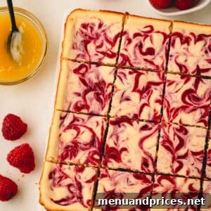 Lemon raspberry cheesecake bars next to fresh raspberries and a bowl of lemon curd.