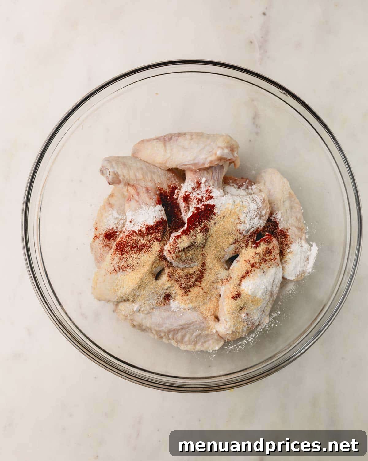 Sticky Sweet Heat Wings 7 Raw chicken wings being tossed with baking powder and seasonings in a large bowl.