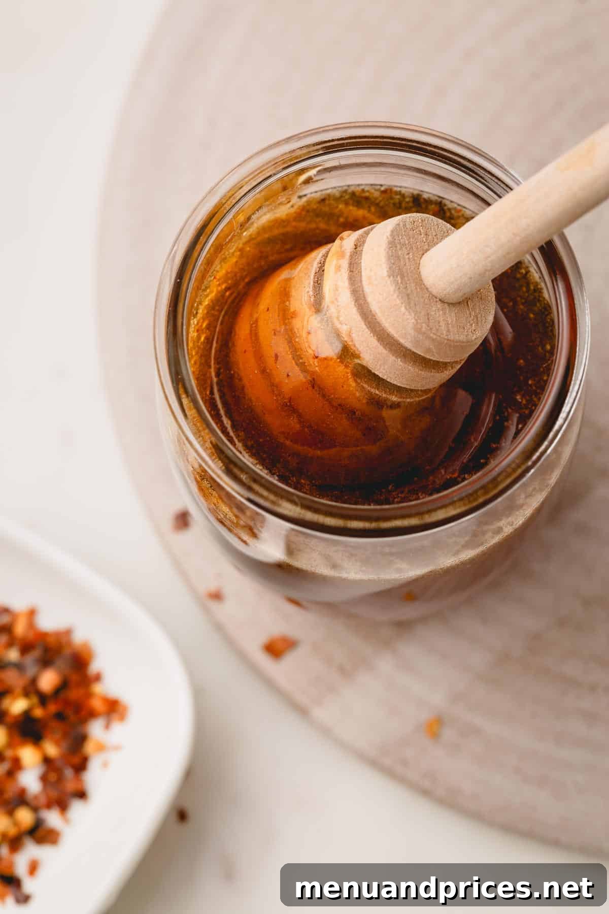 Sweet Heat Honey Formula 7 A jar of homemade hot honey, with a wooden honeycomb dipper artfully sticking out, signifying its natural goodness.