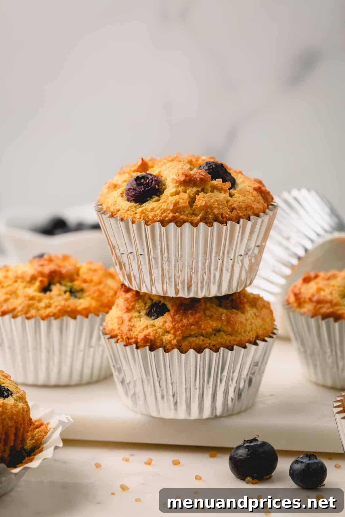 Moist Almond Flour Blueberry Muffins 2 A stack of two almond flour blueberry muffins in muffin liners, highlighting their golden tops and tender texture.