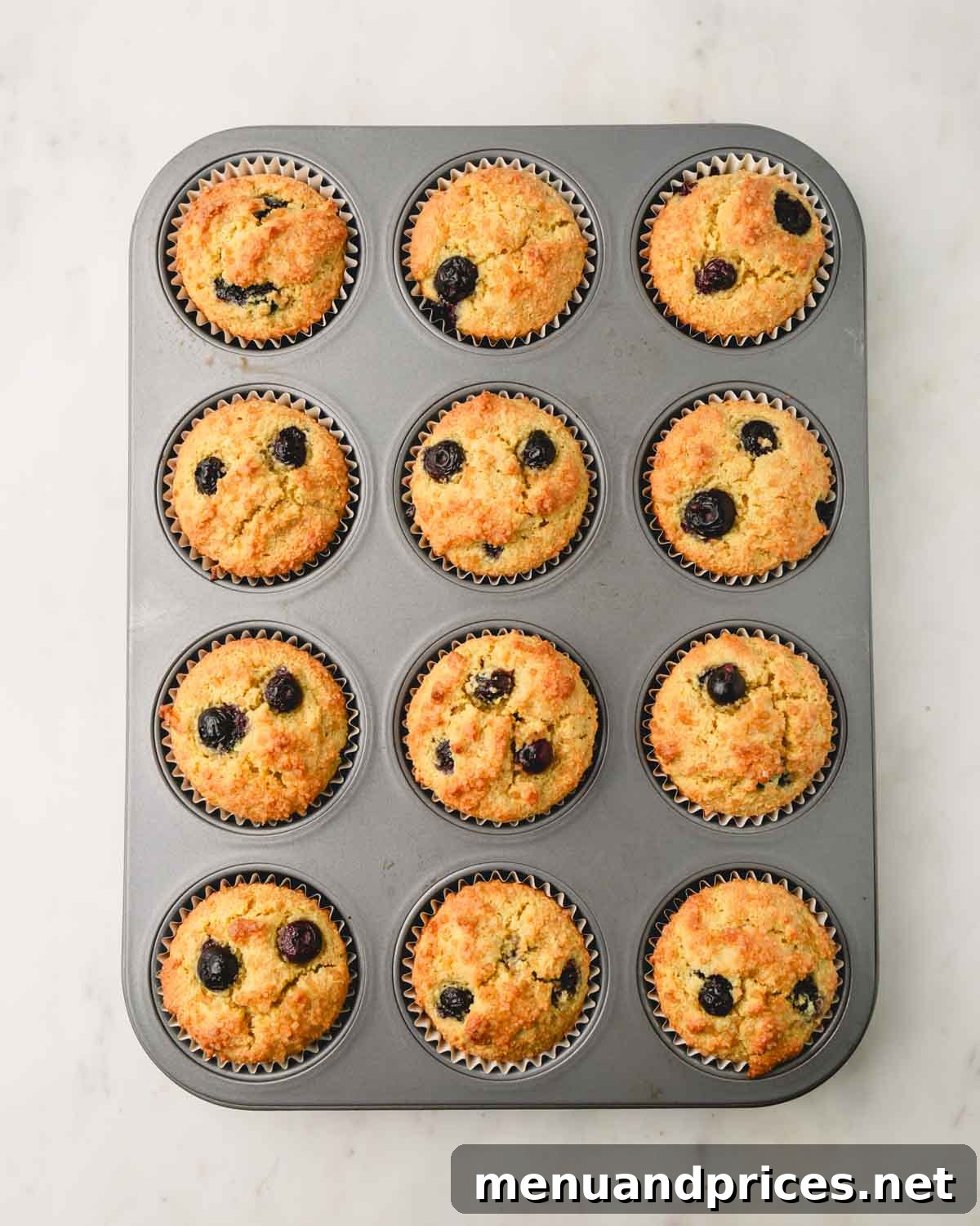 Moist Almond Flour Blueberry Muffins 12 A muffin pan filled with freshly baked, golden-brown almond flour blueberry muffins, showing their perfectly domed tops.