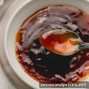 Sticky Honey Teriyaki 11 A spoon lifting a scoop of honey teriyaki sauce from a bowl, highlighting its glossy texture.