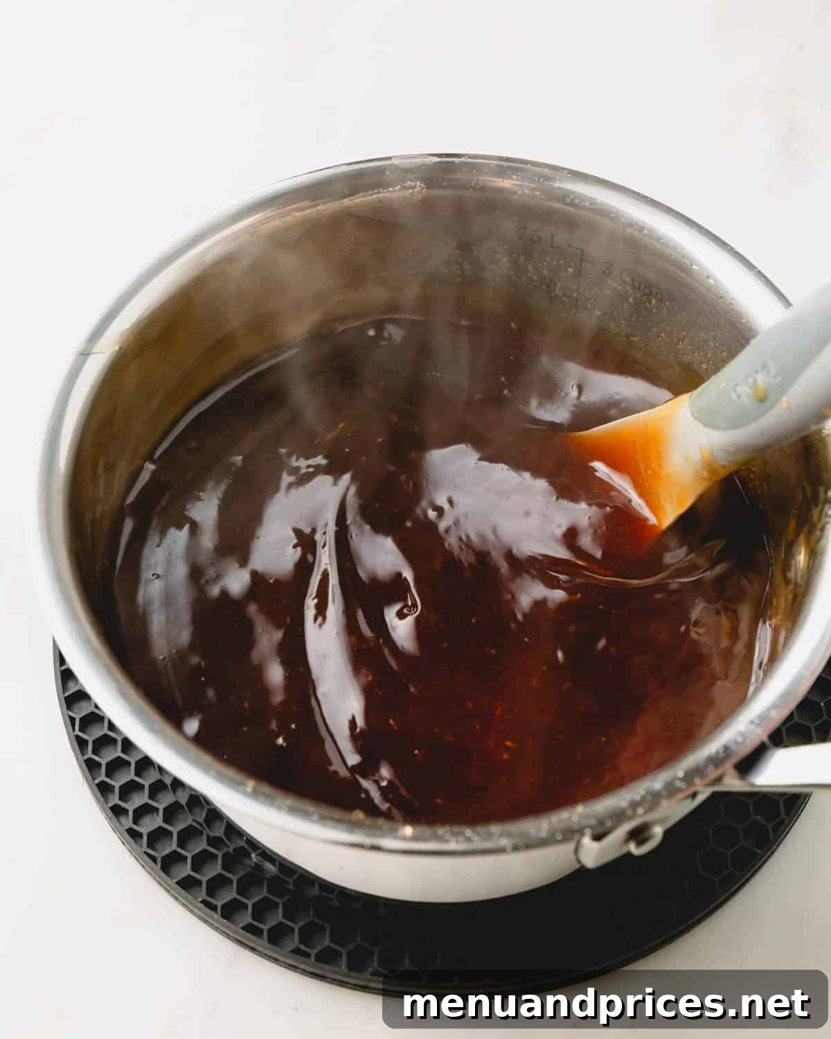 Sticky Honey Teriyaki 3 A pot of golden honey teriyaki sauce being gently stirred on the stovetop, showing its rich texture.