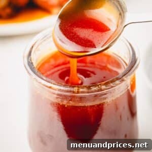 Golden Blaze Drizzle 11 A spoon lifting a scoop of hot honey sauce from a jar.