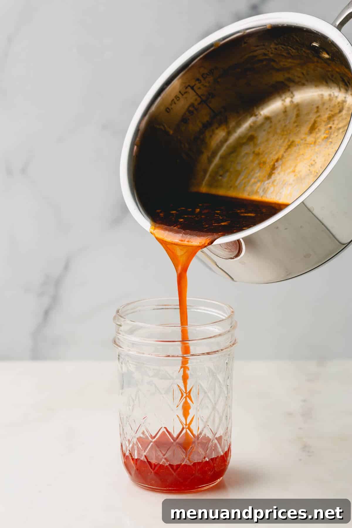 Golden Blaze Drizzle 7 Warm hot honey sauce being poured from a pot into a clear mason jar, ready for cooling and storage.