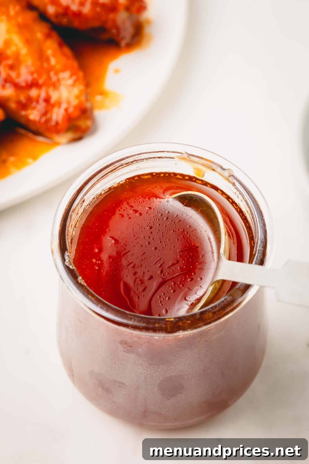 Golden Blaze Drizzle 8 A spoon sticking out of a glass jar filled with glistening hot honey sauce, ready to be served.