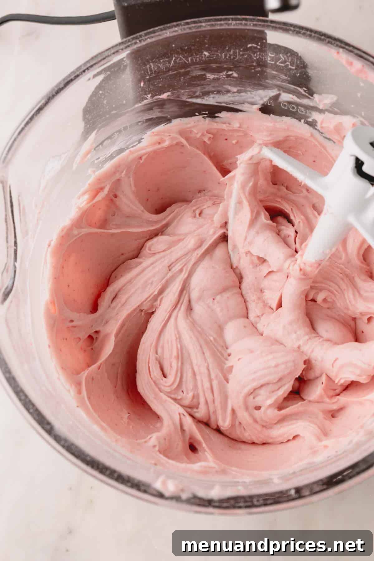 Strawberry Cheesecake Frosting 8 A large bowl of vibrant strawberry cream cheese frosting in a stand mixer, showcasing its smooth texture and rich pink color, ready to be used.