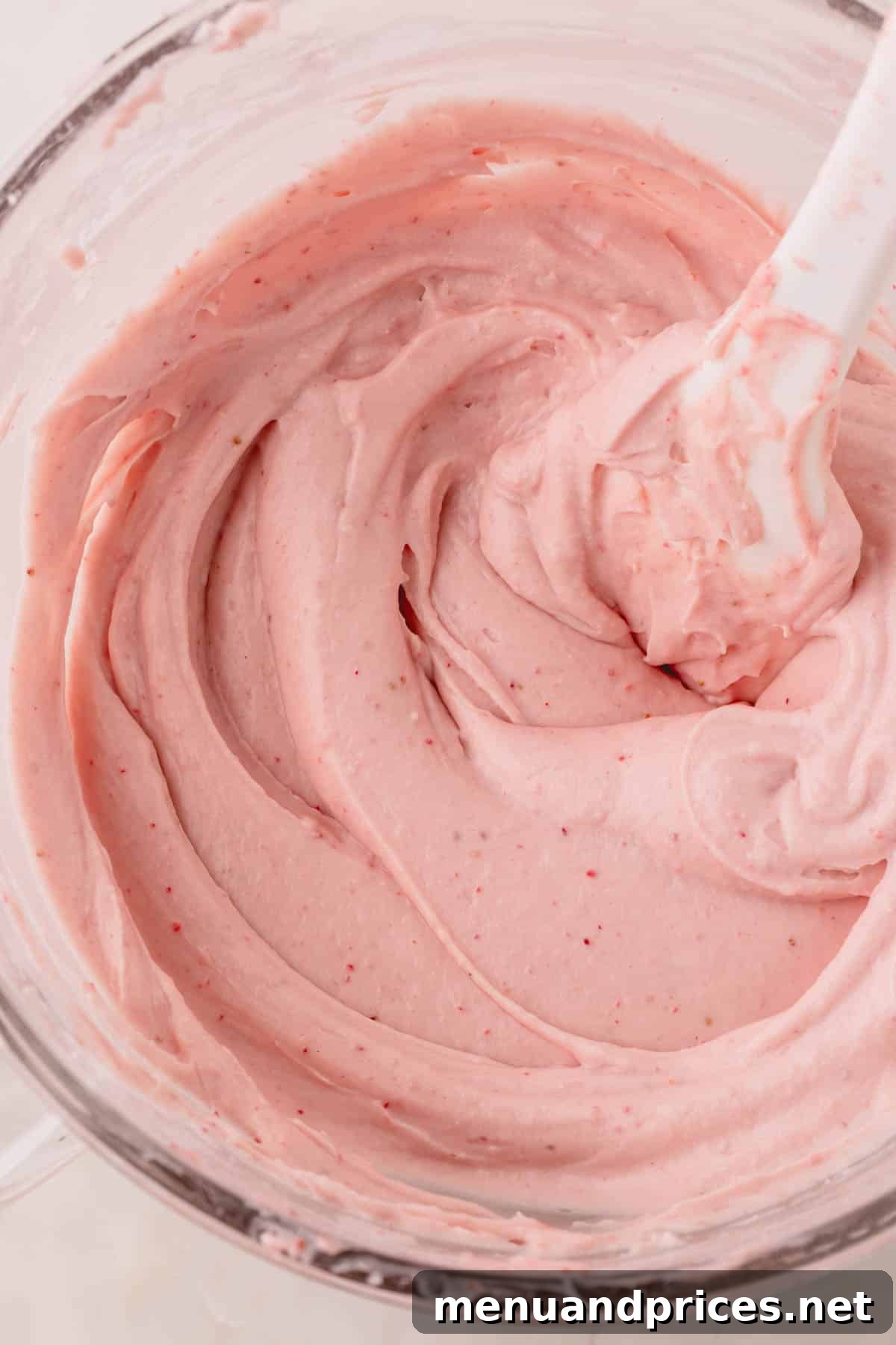 Sweet Strawberry Dream 14 A generous bowl of luscious strawberry cream cheese frosting, with a spatula gracefully resting within, highlighting its smooth, creamy texture.