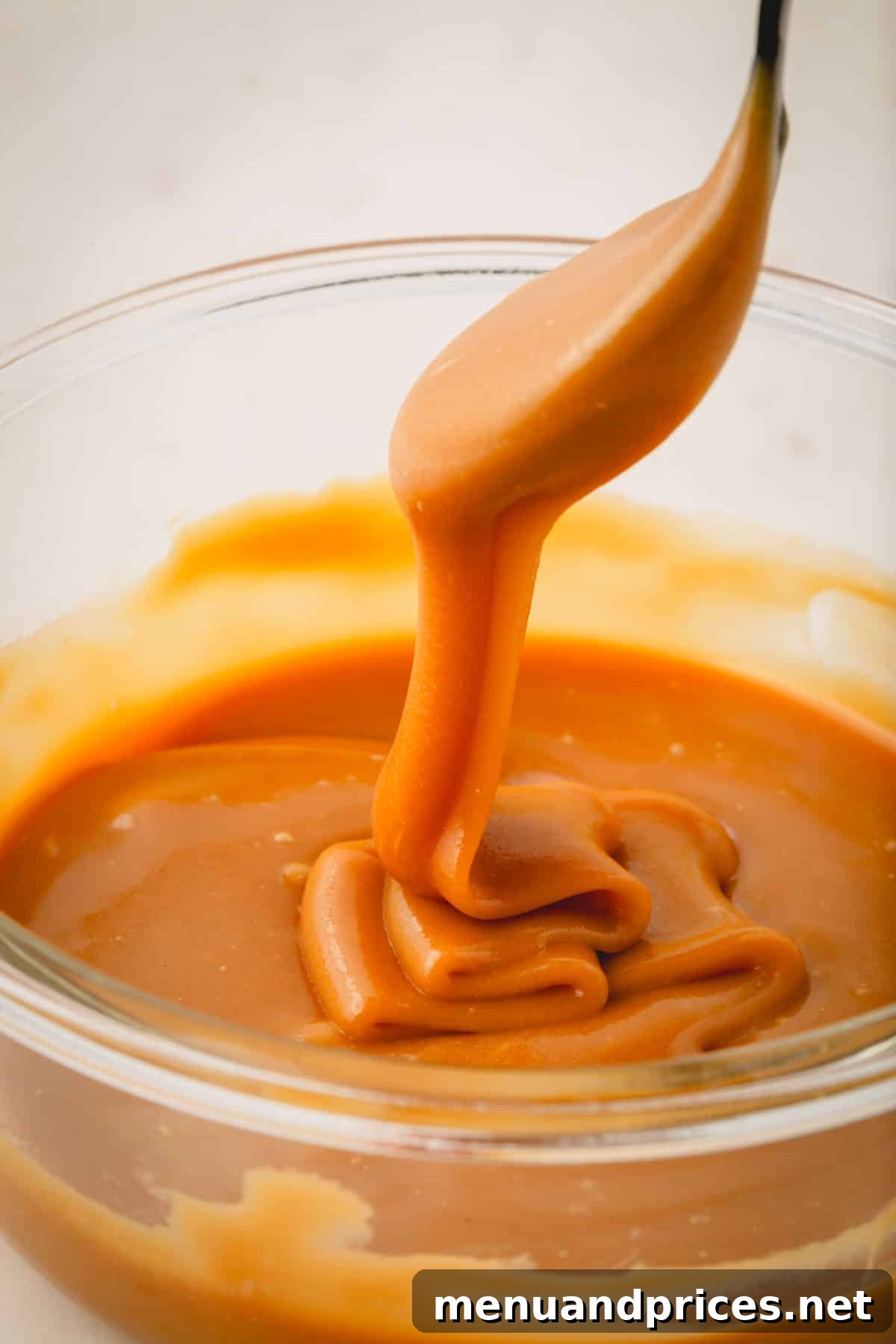 Luscious Plant-Based Caramel Filling 9 Vegan coconut caramel filling being lifted with a spoon, showing its perfect consistency.