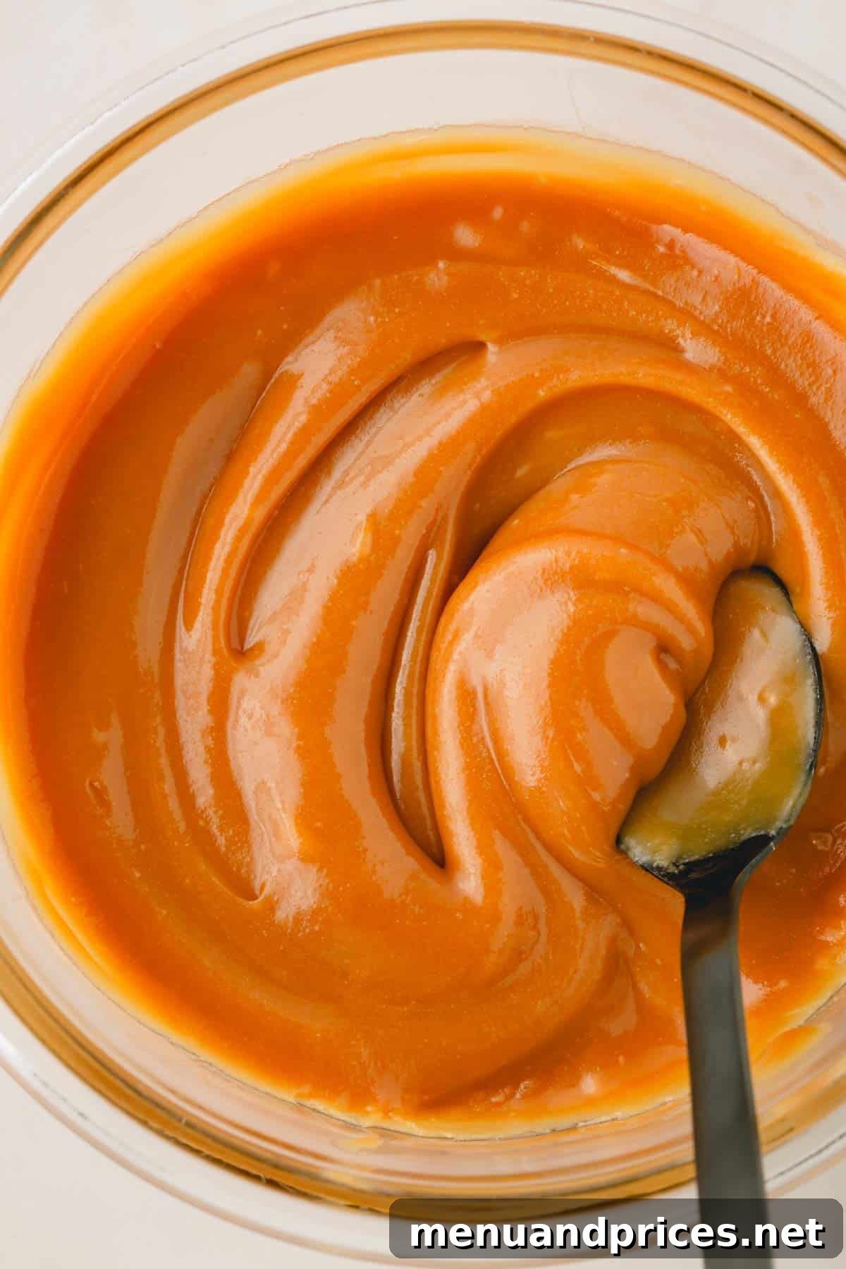 Luscious Plant-Based Caramel Filling 10 A spoon swirling vegan caramel filling in a bowl, showcasing its smooth texture.