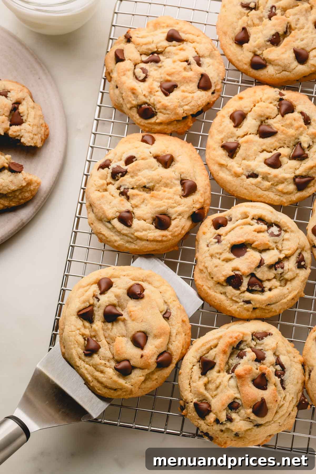 Decadent Thick and Chewy Chocolate Chip Cookies 2 Thick and chewy chocolate chip cookies cooling on a wire rack, with a spatula gently lifting one.