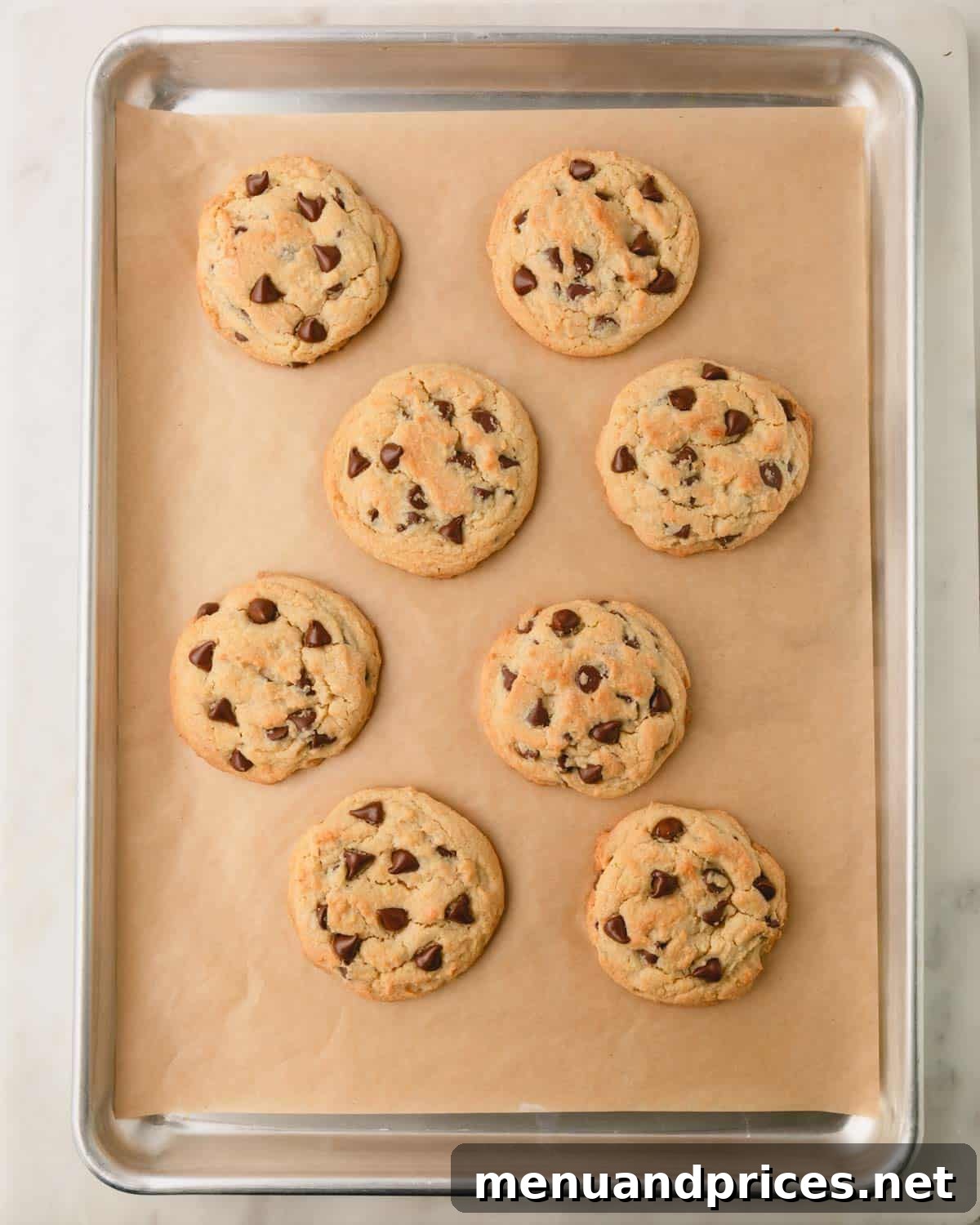 Decadent Thick and Chewy Chocolate Chip Cookies 16 Eight thick and chewy chocolate chip cookies, freshly baked and golden, on a parchment paper-lined baking sheet.