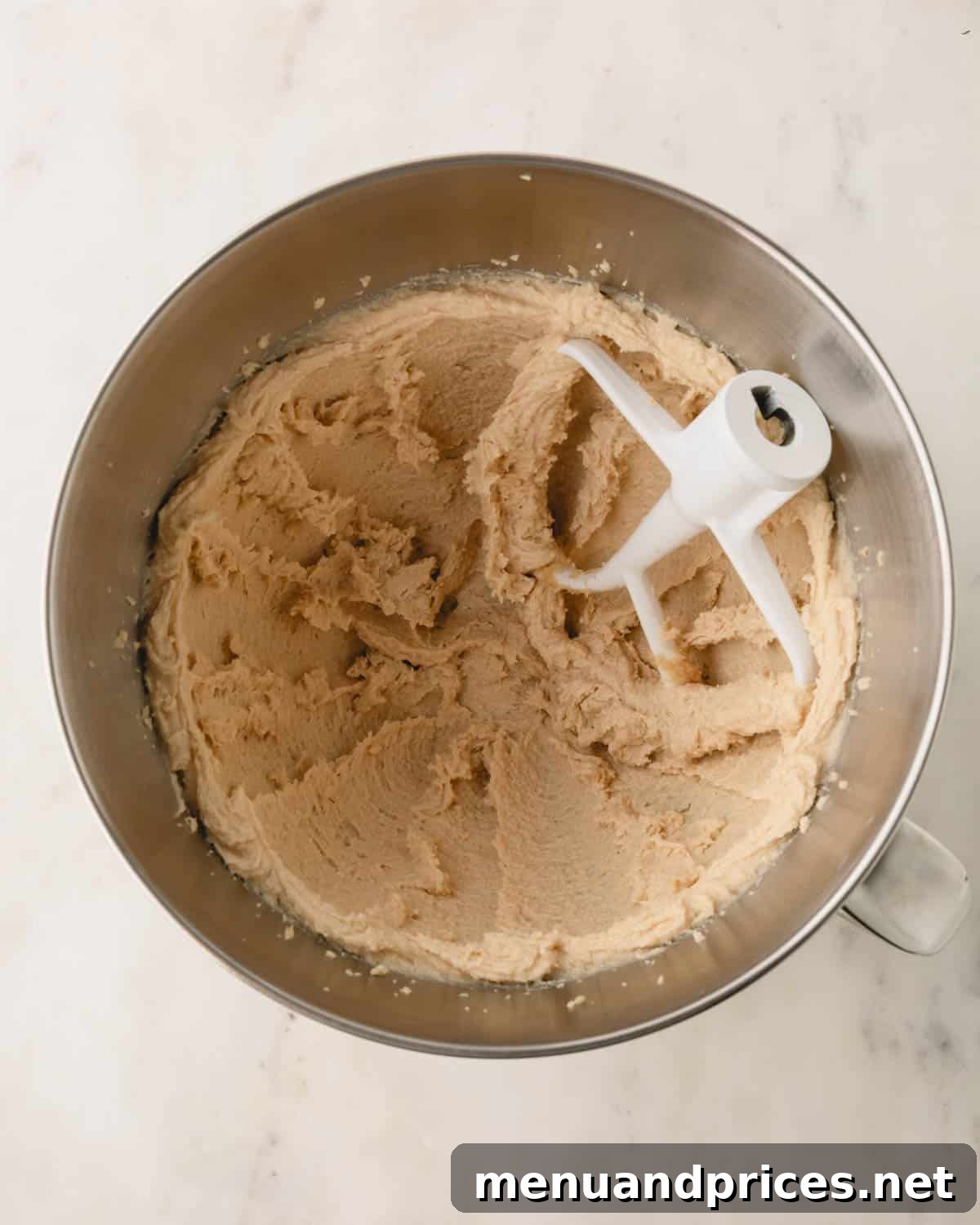 Decadent Thick and Chewy Chocolate Chip Cookies 7 Creamed white sugar, brown sugar, and butter in a bowl after mixing, with a stand mixer paddle attachment present.