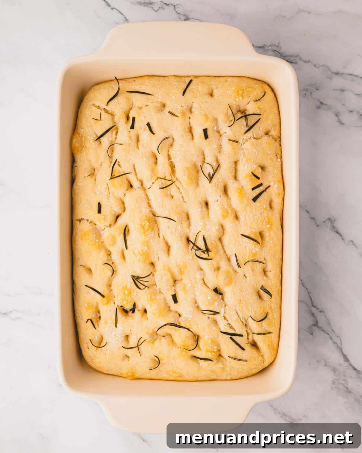 Foolproof Homemade Focaccia 15 A freshly baked rosemary focaccia bread, golden and inviting, still in its baking dish, showcasing its perfect rise and crispy edges.