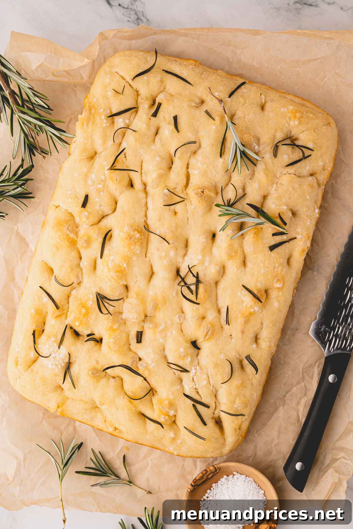 Foolproof Homemade Focaccia 16 A magnificent loaf of golden-brown overnight focaccia bread, generously topped with vibrant rosemary and sparkling flaky salt, resting beautifully on a cooling rack.