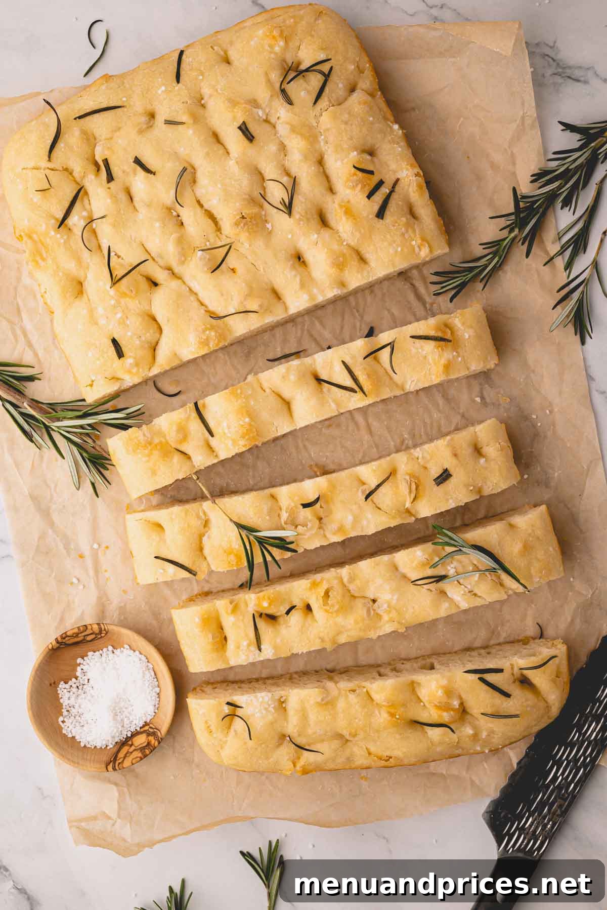 Foolproof Homemade Focaccia 17 Perfectly cut slices of golden rosemary focaccia bread, arranged enticingly on a sheet of parchment paper, highlighting its beautiful texture and rustic charm.