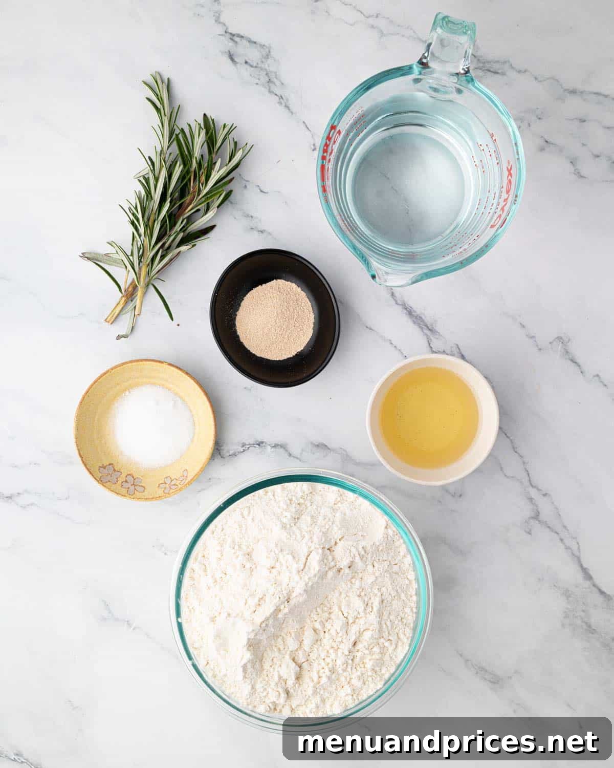 Foolproof Homemade Focaccia 4 A beautifully arranged selection of essential ingredients for making overnight focaccia bread, including flour, salt, yeast, olive oil, and fresh rosemary sprigs.