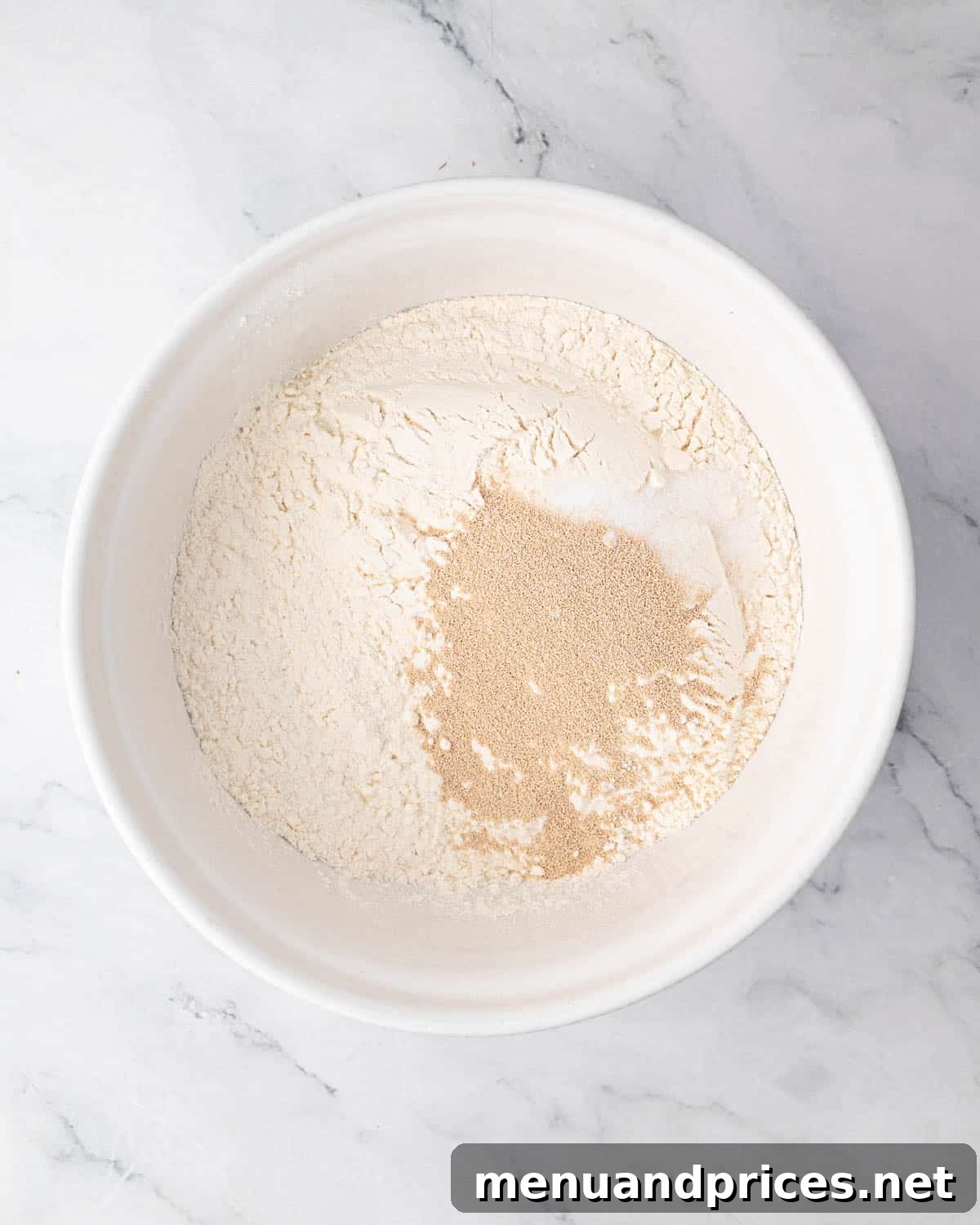 Foolproof Homemade Focaccia 5 A bowl containing precisely measured dry ingredients for focaccia bread – flour, salt, and instant yeast – ready for mixing.