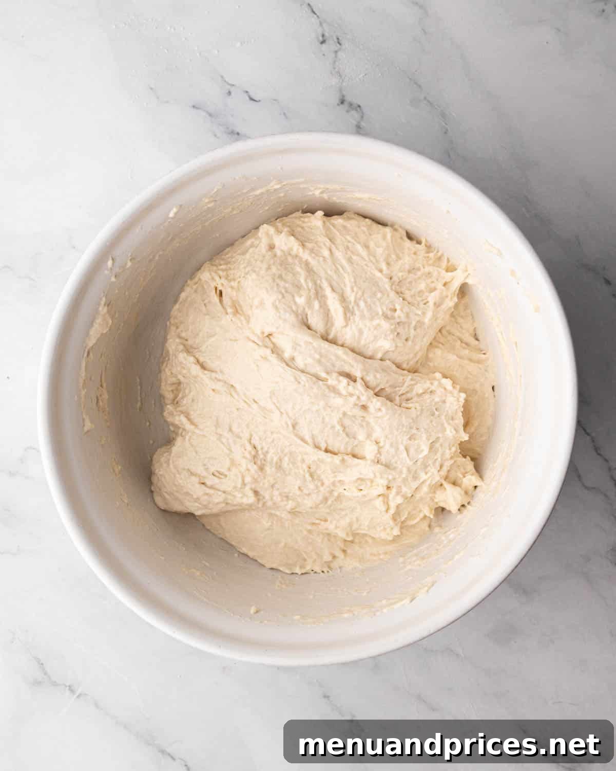 Foolproof Homemade Focaccia 9 Focaccia dough in a bowl during the stretch-and-fold process, showing the dough being carefully folded over itself.