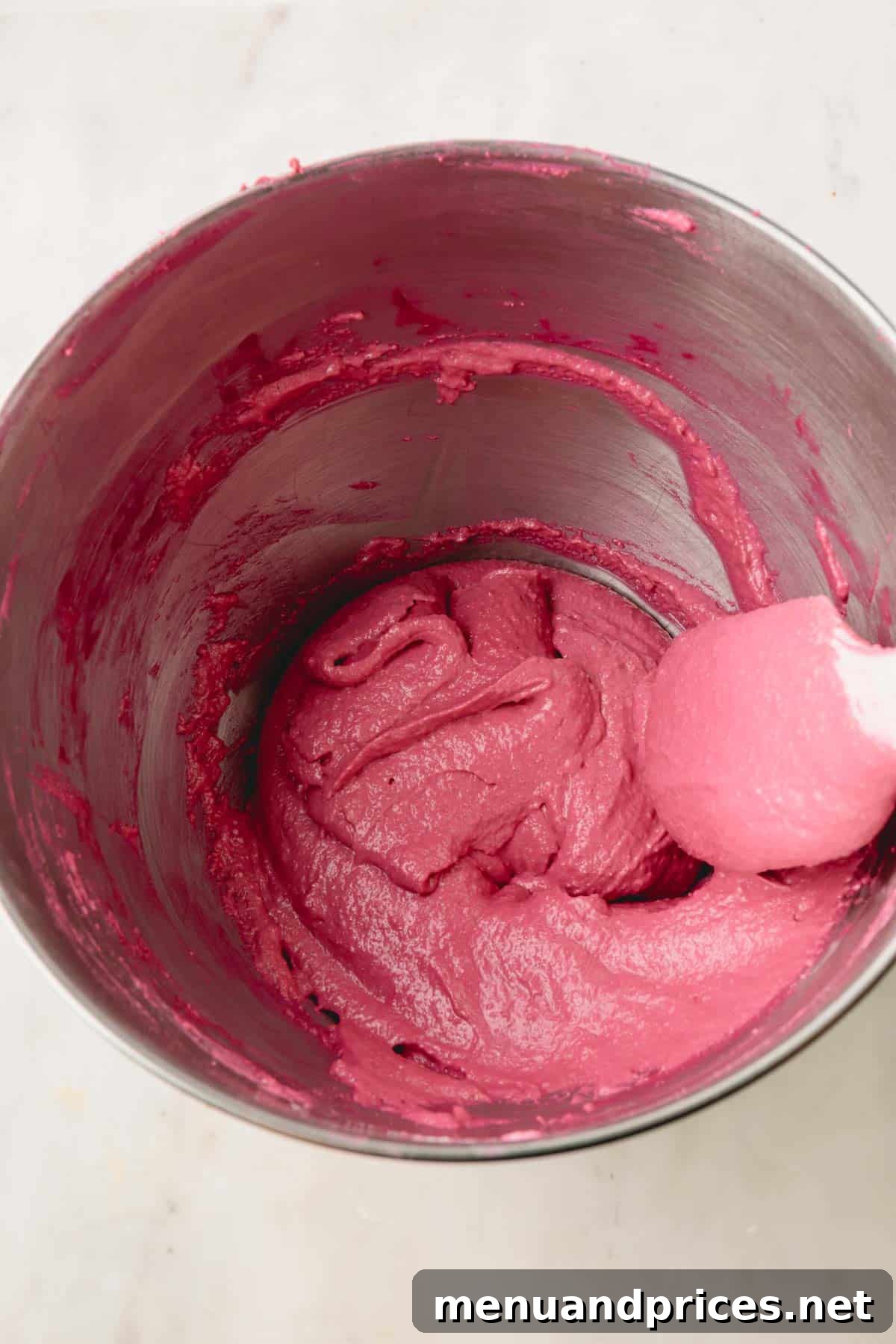 A large bowl filled with smooth, consistent cranberry macaron batter.