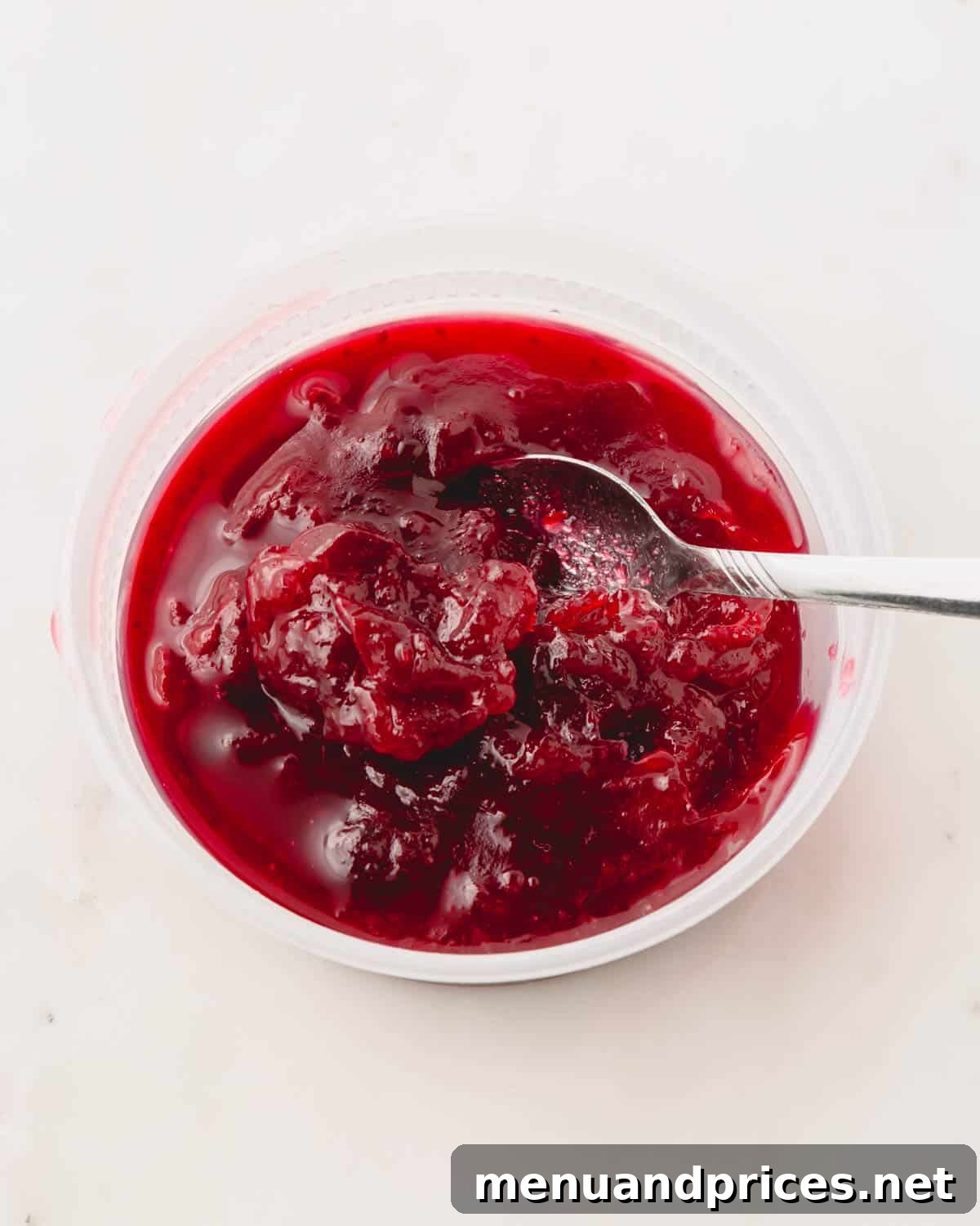 Cranberry sauce thickening over medium heat in a saucepan, showing its vibrant color.
