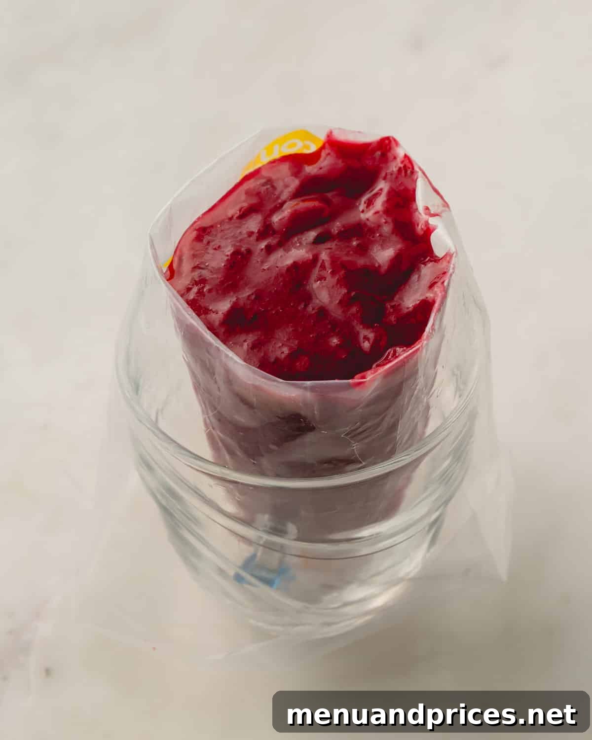 Smooth cranberry sauce being blended with an immersion blender in a saucepan.