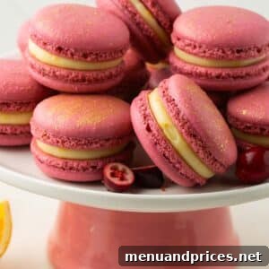 A platter of beautifully arranged orange cranberry macarons, glistening with a dusting of gold.