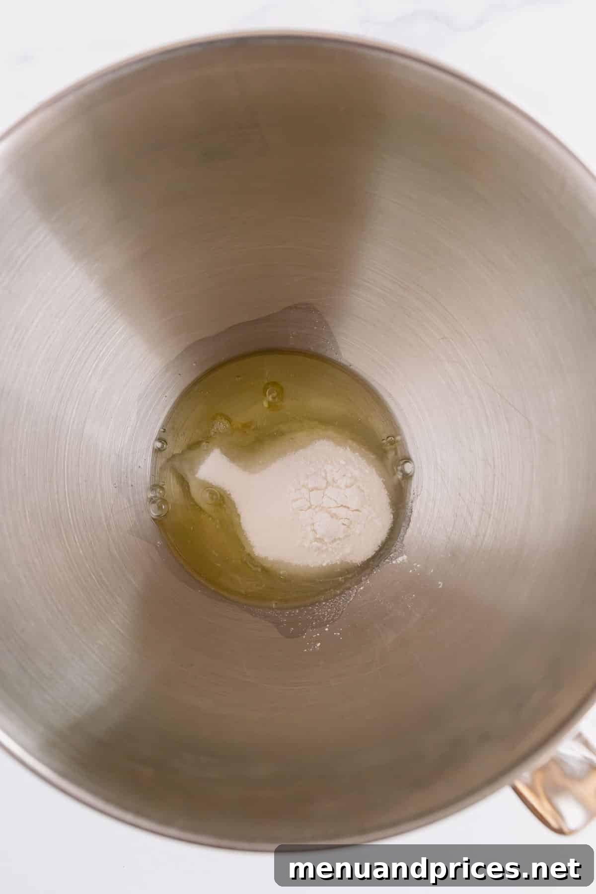 Egg whites, sugar, cream of tartar, and salt meticulously measured in a shining stainless steel mixer bowl.