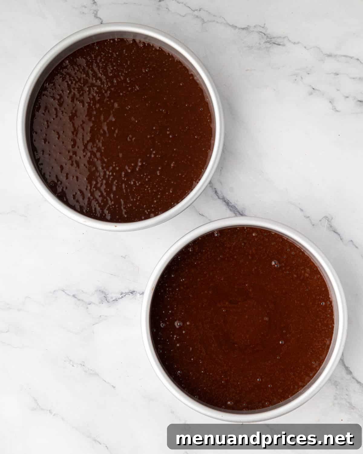 Two round cake pans filled with rich chocolate cake batter, ready for the oven.