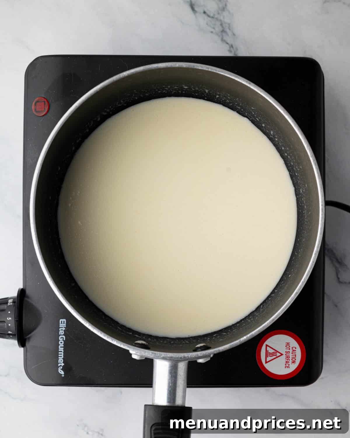 Heavy cream being gently heated in a small saucepan for ganache preparation.