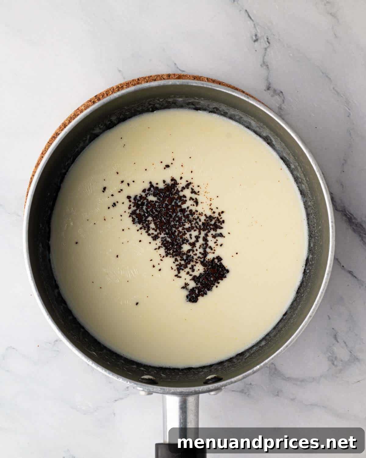 Espresso powder dissolving into hot heavy cream in a saucepan, enhancing chocolate flavor.