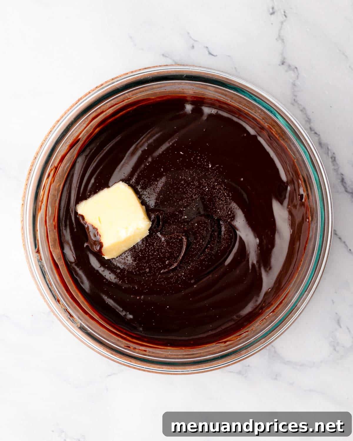 A knob of unsalted butter being added to the warm chocolate ganache, to be emulsified for extra richness.