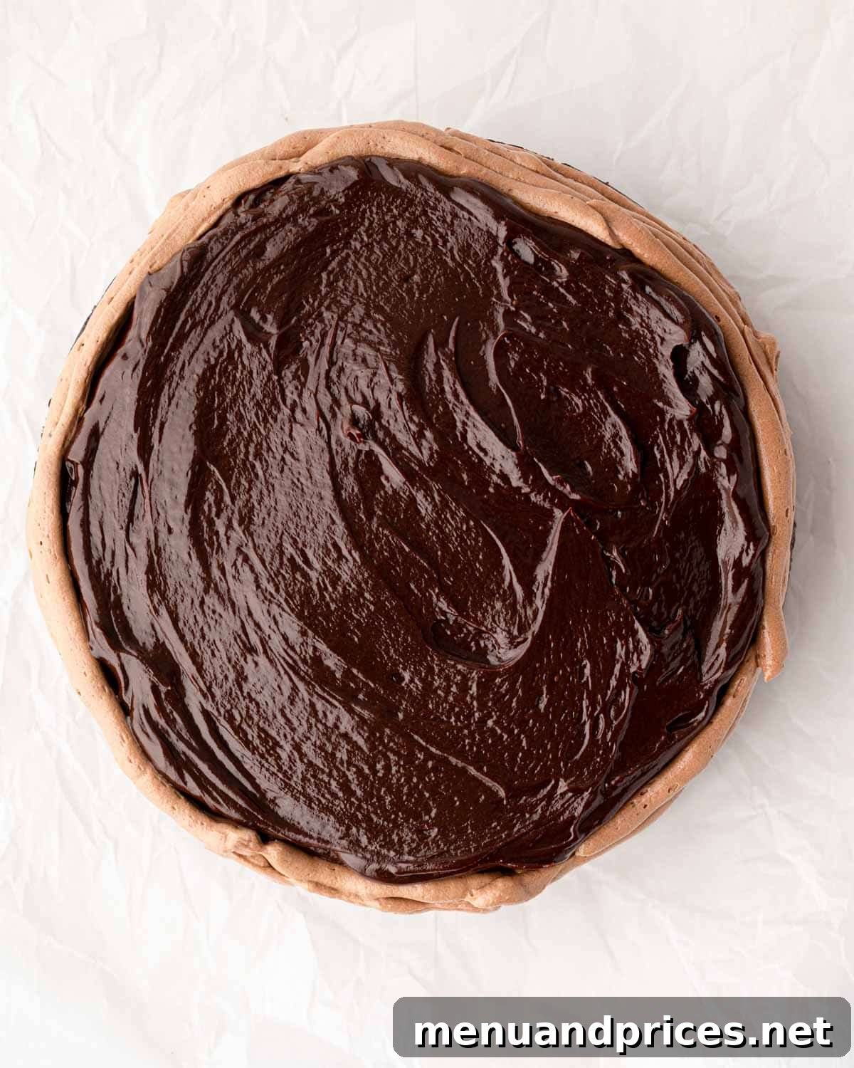 A buttercream dam expertly piped around a round chocolate cake, ready to hold the ganache filling.