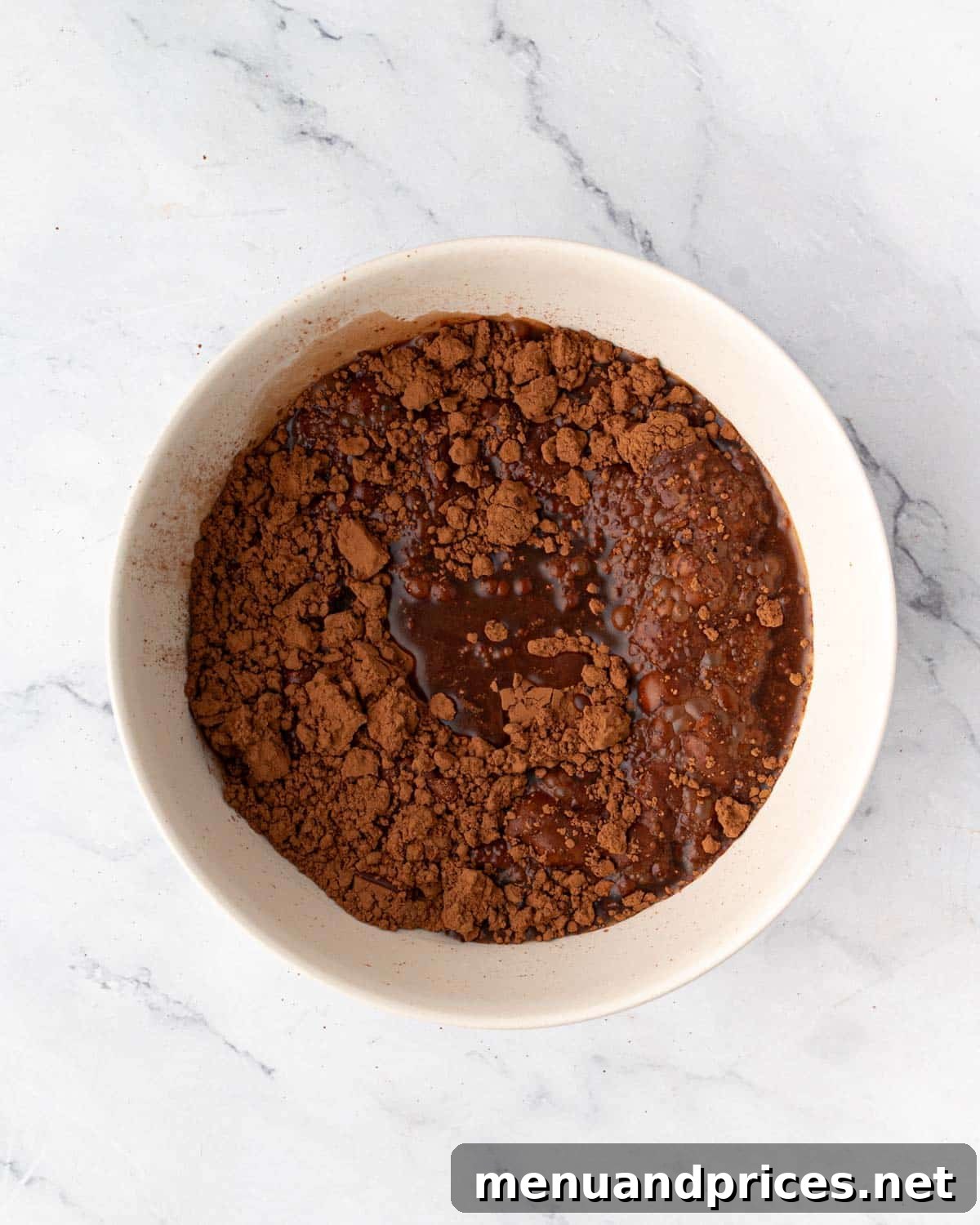 Cocoa powder being sifted into a bowl of hot water for blooming.