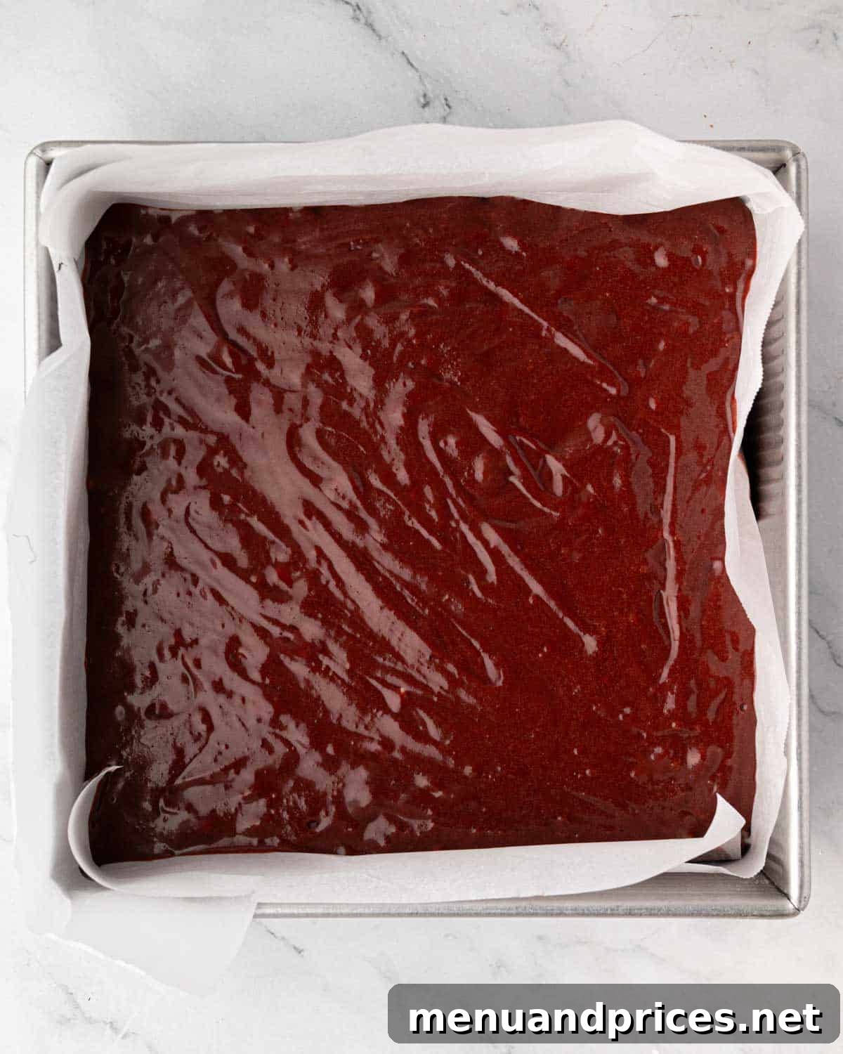 Crimson Velvet Brownies 13 Uncooked red velvet brownie batter smoothly spread in a square baking pan, ready for the oven.