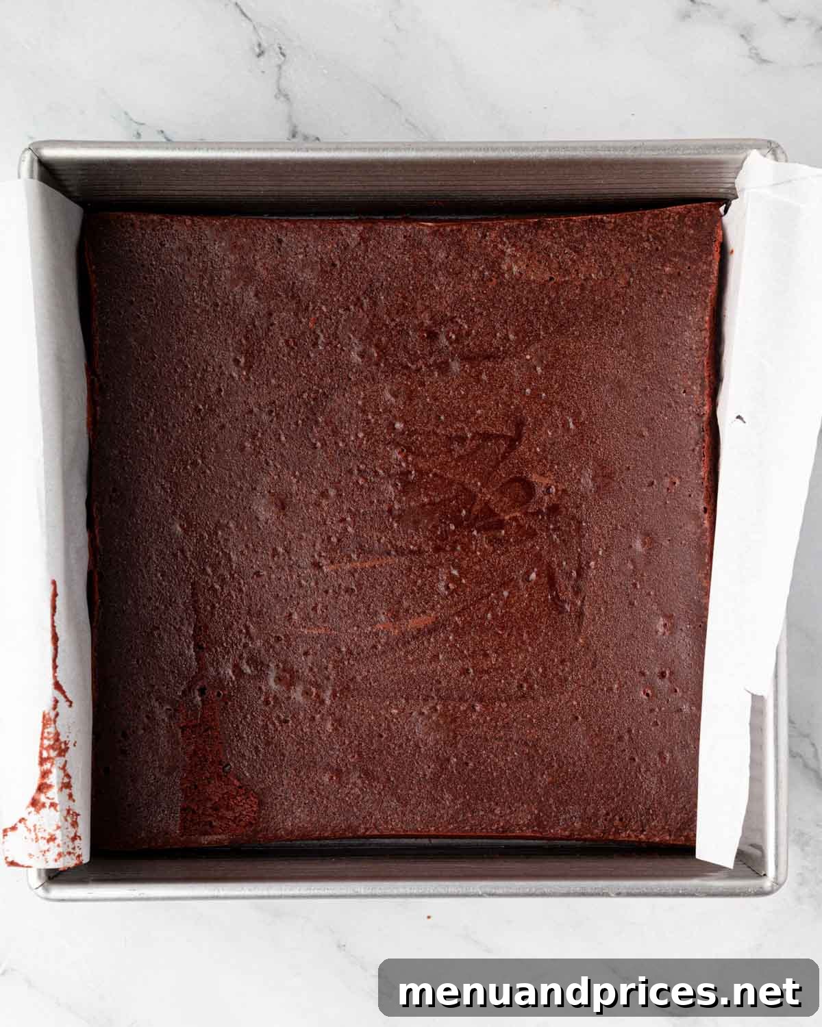 Crimson Velvet Brownies 14 Beautifully baked red velvet brownies, golden at the edges and set, still in the parchment-lined square baking pan.