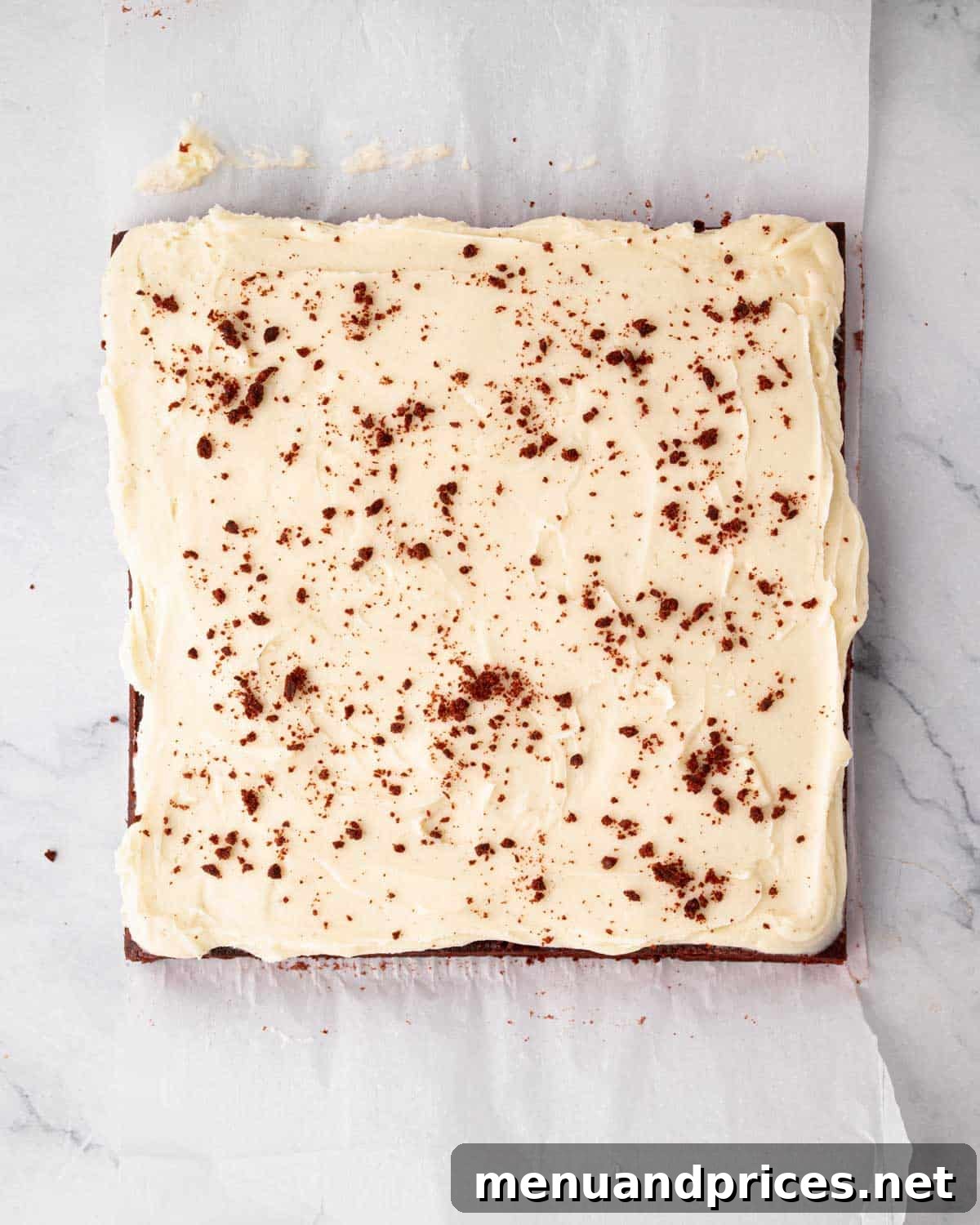 Crimson Velvet Brownies 18 A rich slab of red velvet brownies, meticulously topped with cream cheese frosting and a light dusting of cocoa powder.