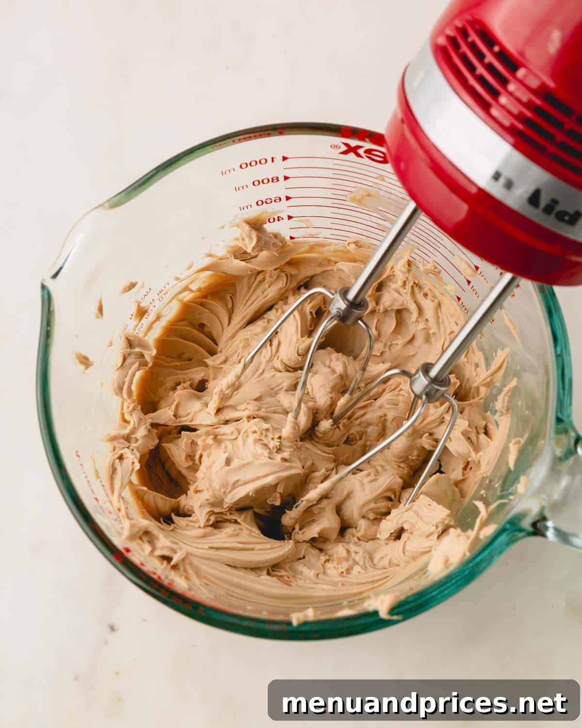 Espresso Dream Macarons 23 Tiramisu ganache is being whipped with a handheld electric mixer.