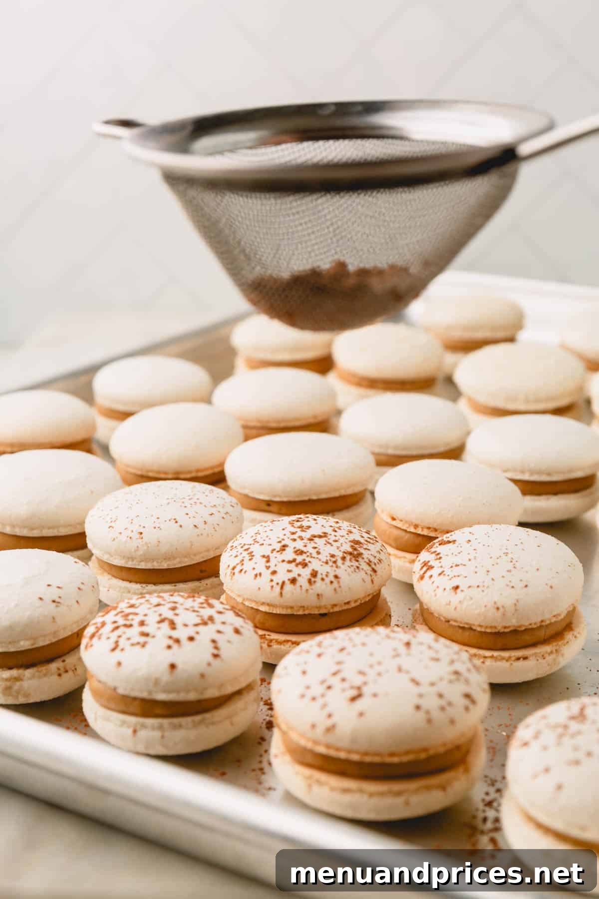 Espresso Dream Macarons 28 Cocoa powder is being sifted over the assemble tiramisu macarons.