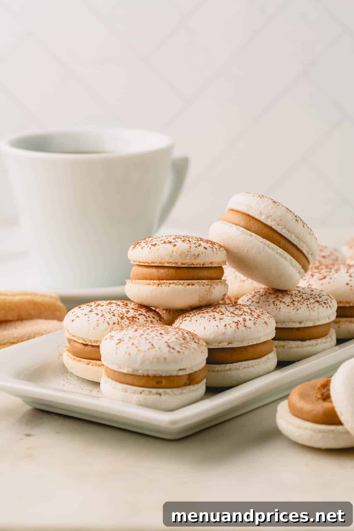 Espresso Dream Macarons 31 Tiramisu macarons stacked on a long white serving plate.
