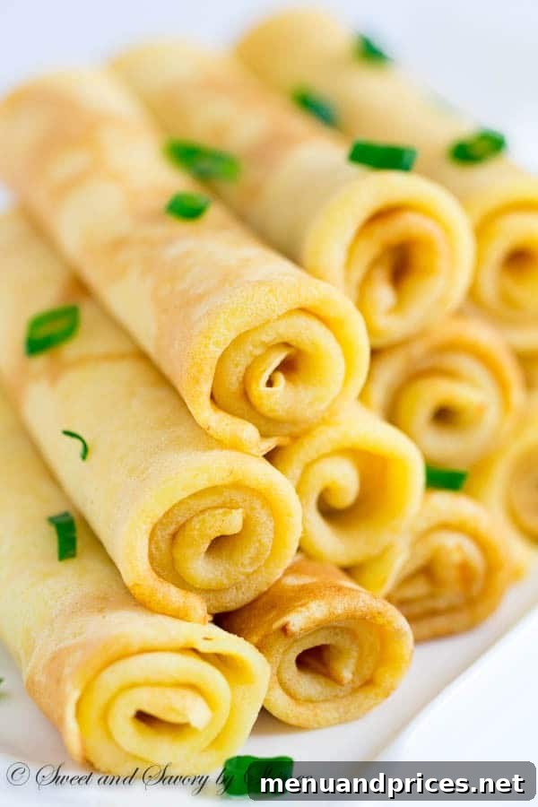 Delicate savory cheese crepes, rolled into elegant cigars and presented on a serving platter, ready to be enjoyed as an appetizer or light meal.