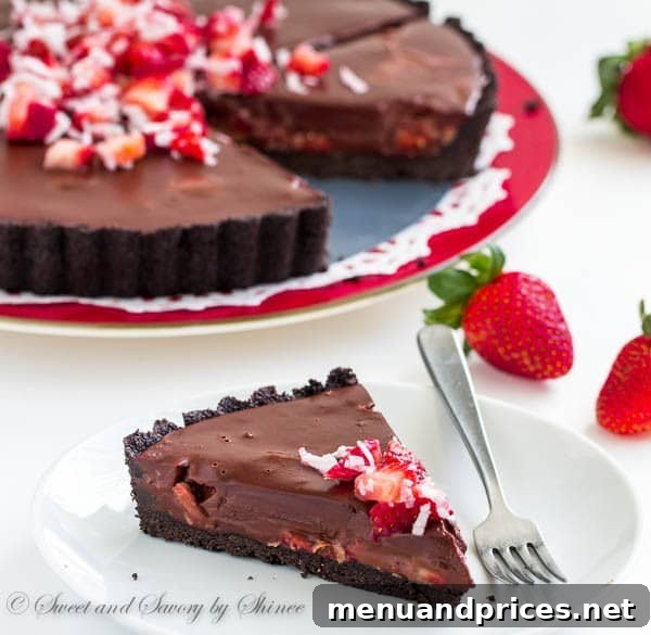 Decadent Chocolate Dream Tart 3 Close-up of a slice of chocolate truffle tart, revealing the layers of ganache, strawberries, and coconut.
