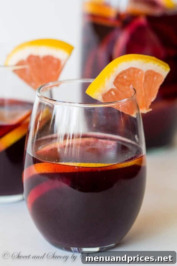 Zesty Grapefruit Sangria 3 Close-up of a pitcher filled with grapefruit sangria, showcasing the beautiful red hue and sliced citrus.