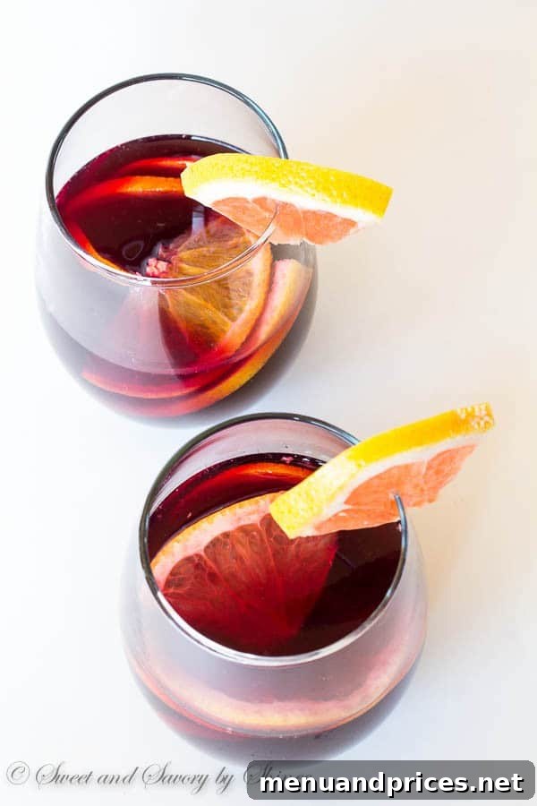 Zesty Grapefruit Sangria 4 Individual glasses of grapefruit sangria on a rustic wooden table, ready for a gathering.
