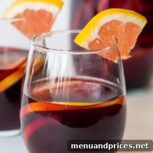 Grapefruit Sangria in a pitcher with sliced fruit and a glass.