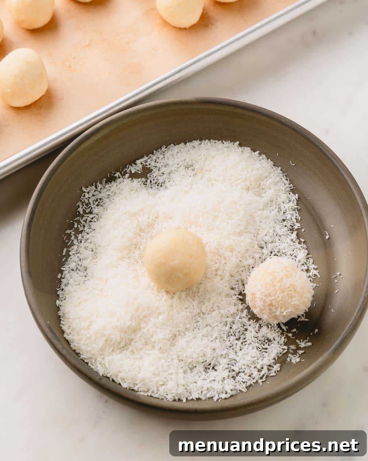 Almond Coconut Delights 11 Coconut balls in a bowl of desiccated coconut.