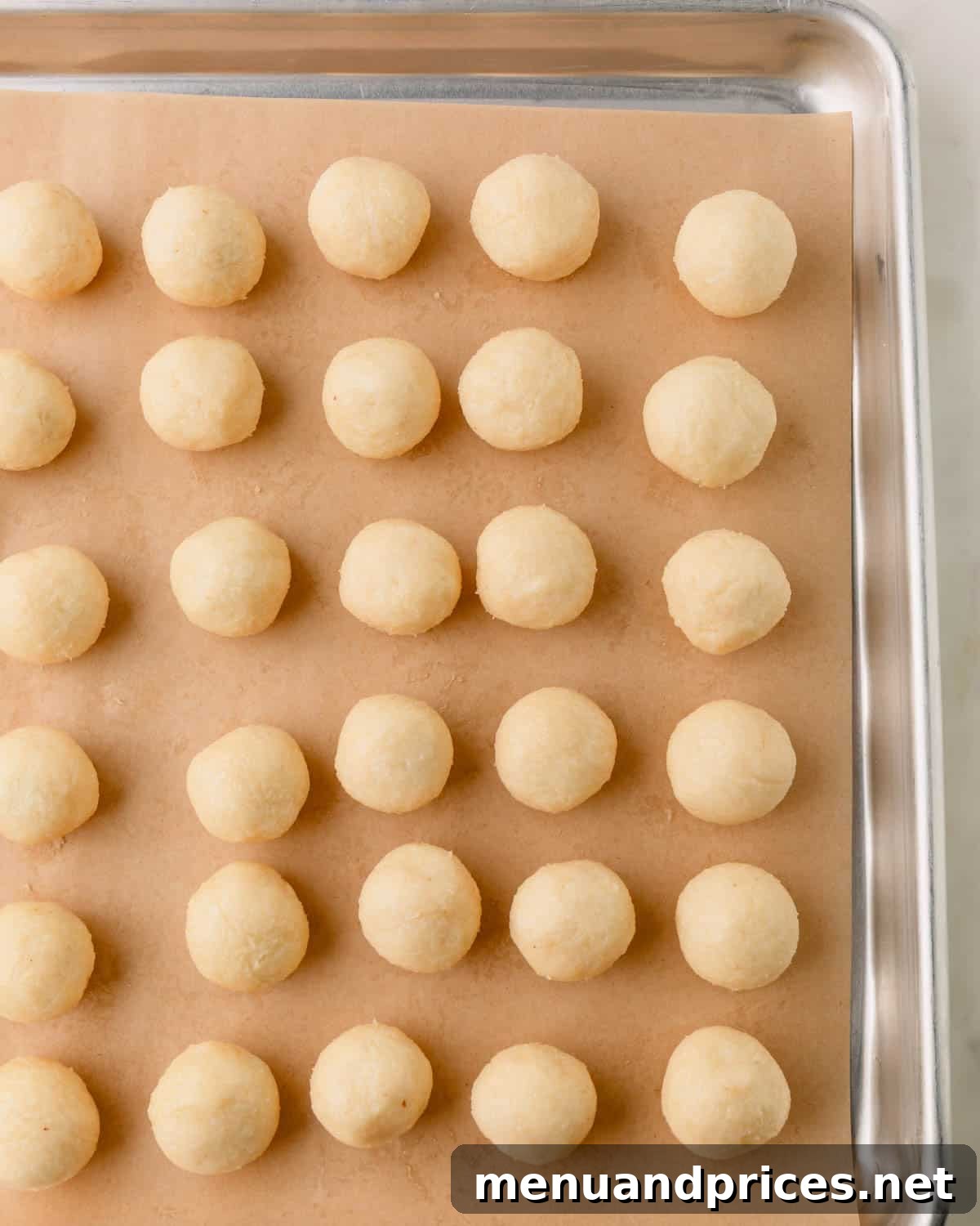 Almond Coconut Delights 13 A parchment-paper lined baking sheet with almond coconut balls.