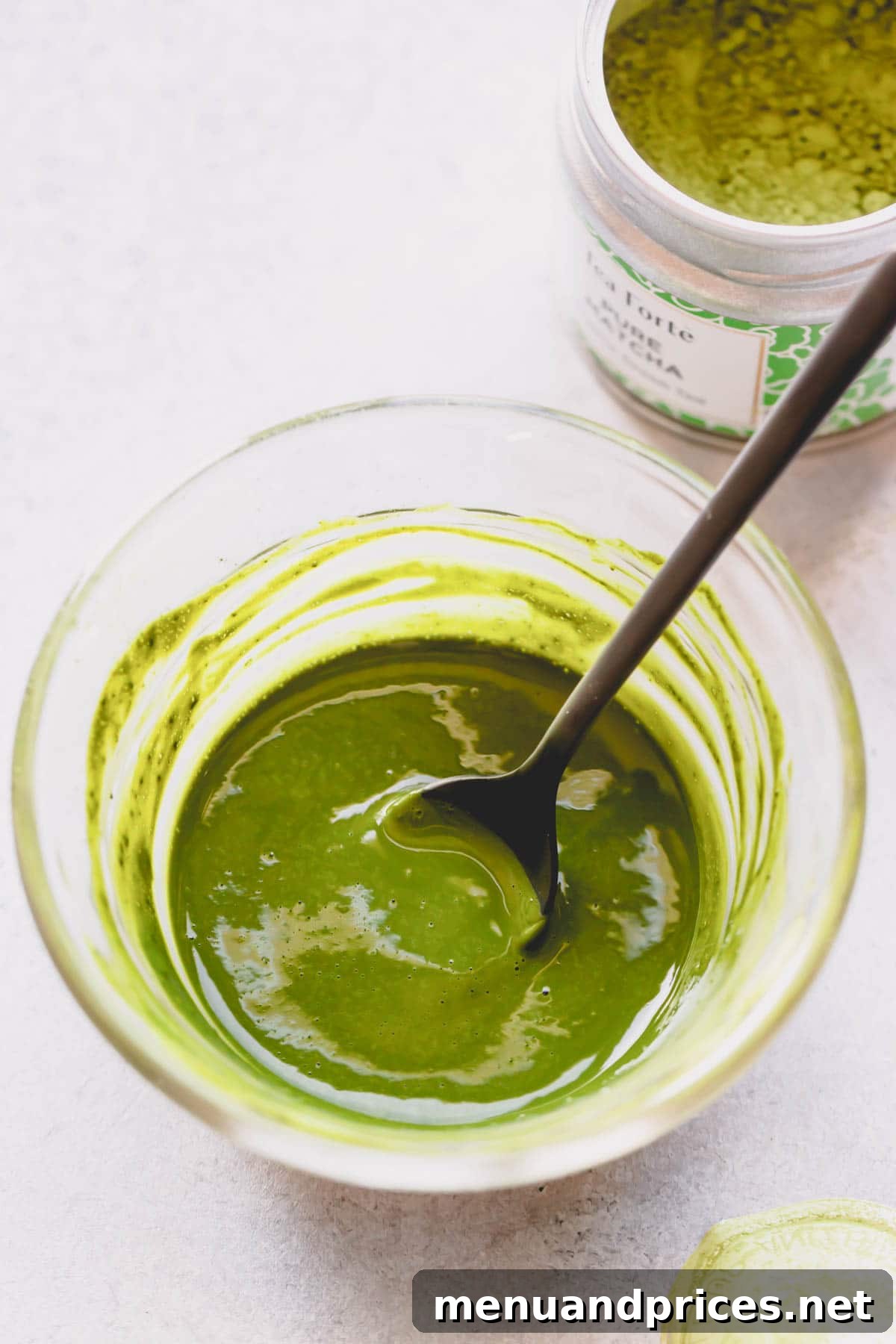 Matcha powder mixed with water in a small bowl, forming a paste.